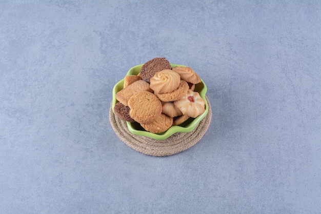 Un piatto verde con deliziosi biscotti rotondi dolci su tela di sacco