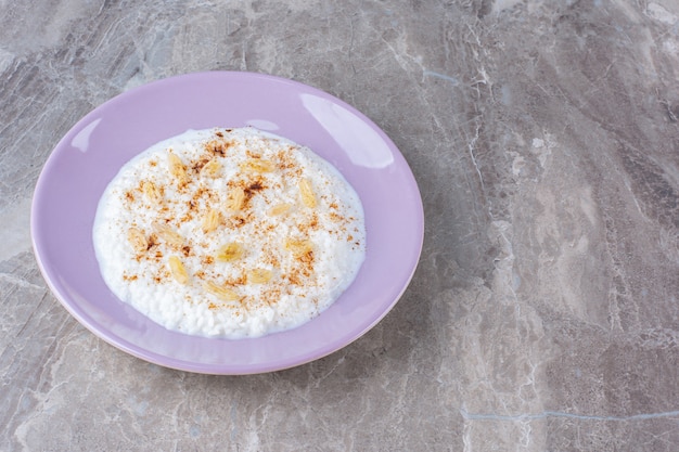Un piatto viola pieno di porridge di farina d'avena sano con polvere di cannella.