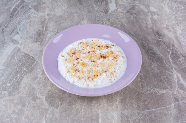 Un piatto viola pieno di sano porridge di farina d'avena con cannella in polvere