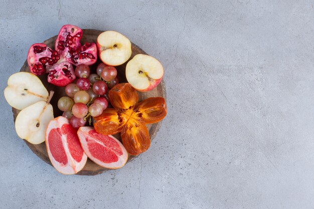 Un piccolo assortimento di frutta su una tavola di legno su sfondo di marmo.