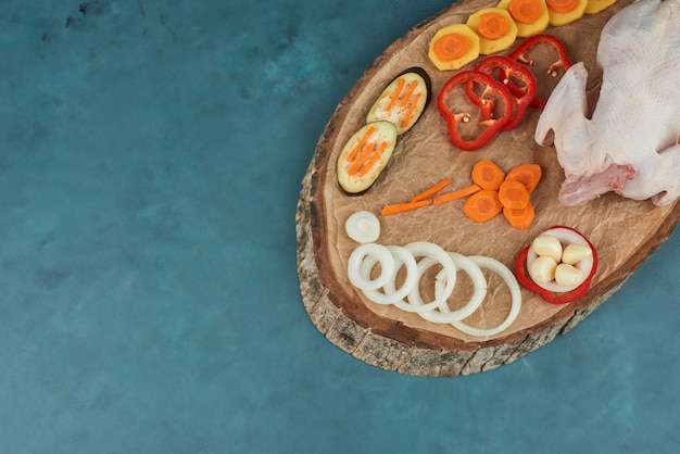 Un pollo con le verdure su una tavola di legno.