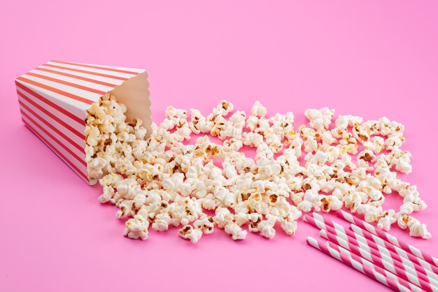 Un popcorn fresco di vista frontale salato si è diffuso tutto sul seme di mais rosa, spuntino di film