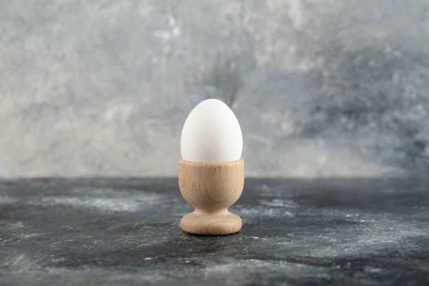 Un portauovo in legno con uovo di gallina bollito.