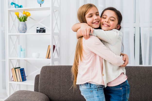 Un primo piano di due ragazze sorridenti che si abbracciano a casa