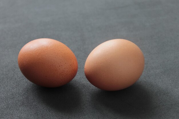 Un primo piano di due uova crude su un tavolo grigio