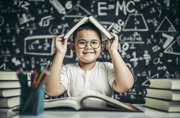 Un ragazzo con gli occhiali ha studiato e messo un libro in testa in classe.