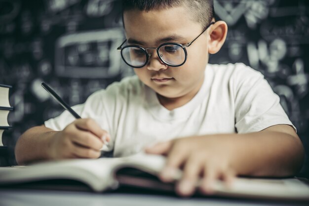 Un ragazzo con gli occhiali uomo che scrive in classe