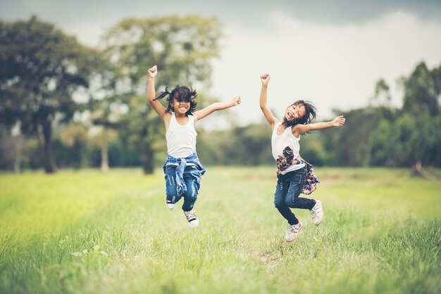 Un salto felice delle due bambine nel parco naturale