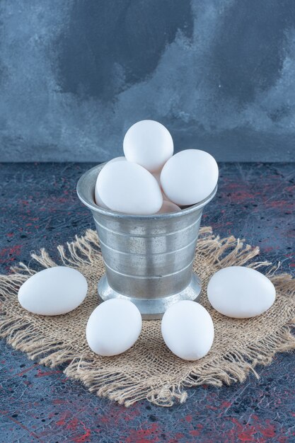 Un secchio metallico con uova di gallina fresche crude.