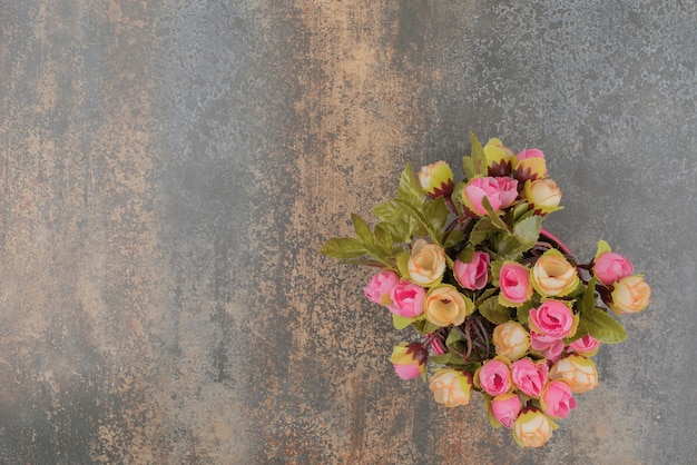 Un secchio rosa con bouquet di fiori sulla superficie in marmo.