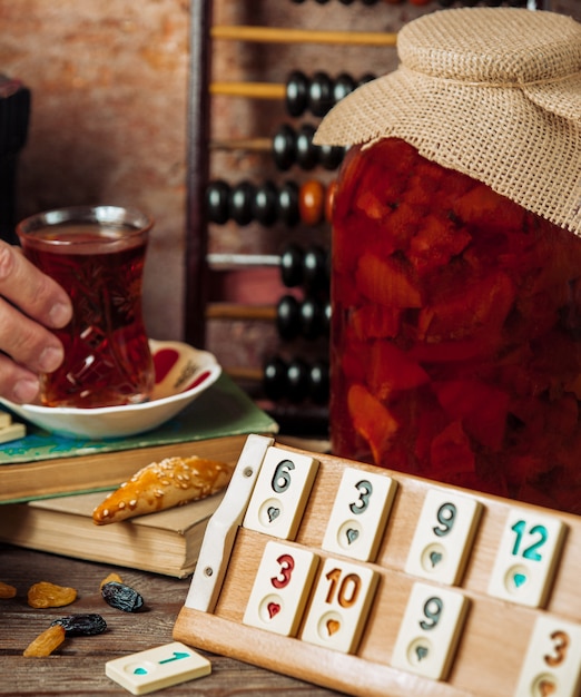 Un set da tè intorno a un gioco, tavolo da domino con un grande barattolo di confettura.
