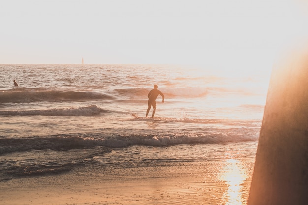 Un surfista che corre sulla spiaggia