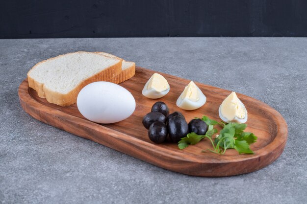 Un tagliere di legno con uovo sodo e fette di pane. Foto di alta qualità