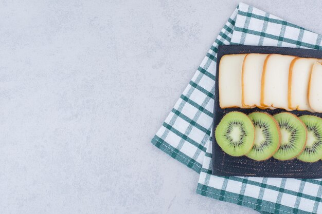 Un tagliere scuro con fette di pane e kiwi fresco. Foto di alta qualità