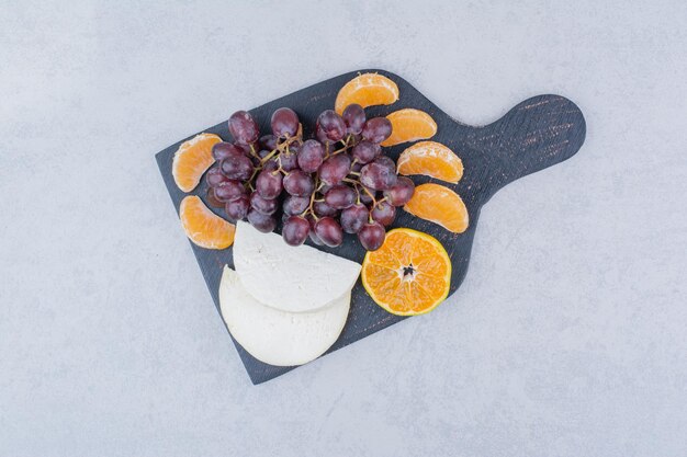 Un tagliere scuro con formaggio a fette e frutta. Foto di alta qualità