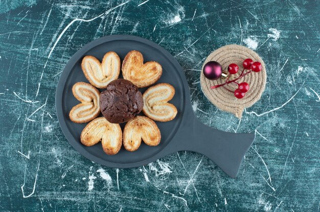 Un tagliere scuro con muffin al cioccolato e biscotti. Foto di alta qualità