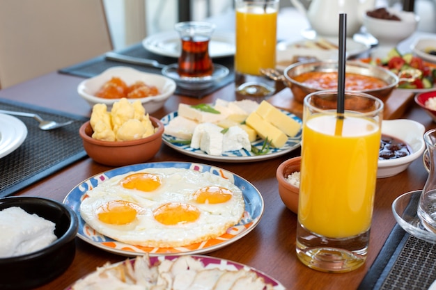 Un tavolo per la colazione vista frontale con uova panini formaggio e succo di frutta fresco nel ristorante durante la colazione del pasto diurno
