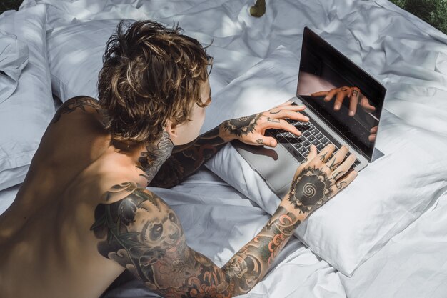 un uomo a letto che lavora a un laptop, controlla la posta, guarda un film, ascolta la musica