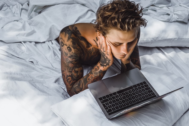 un uomo a letto che lavora a un laptop, controlla la posta, guarda un film, ascolta la musica