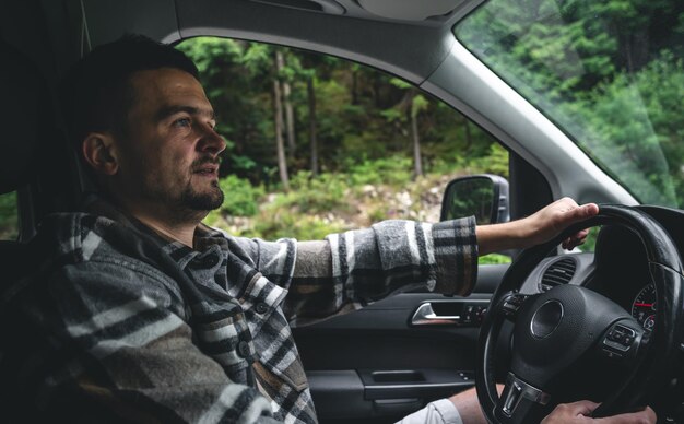 Un uomo alla guida di un'auto viaggia in un'area forestale di montagna