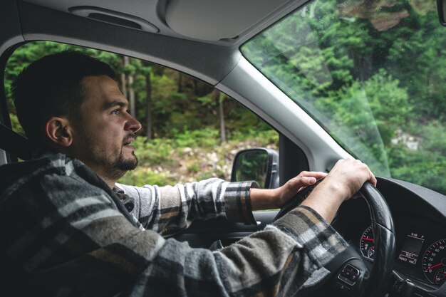 Un uomo alla guida di un'auto viaggia in un'area forestale di montagna