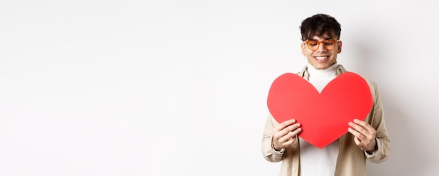 Un uomo bello ed elegante con gli occhiali da sole prepara una cartolina a sorpresa per la fidanzata il giorno di san valentino ho