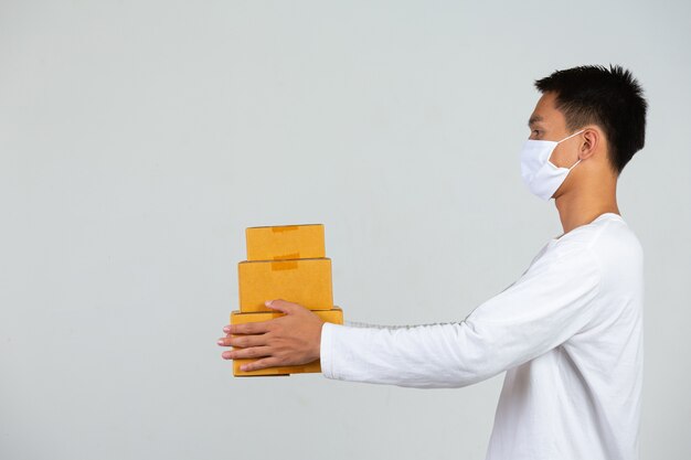 Un uomo che indossa una maglietta bianca tiene in mano una cassetta postale marrone per consegnare le cose. Fai gesti ed espressioni facciali.