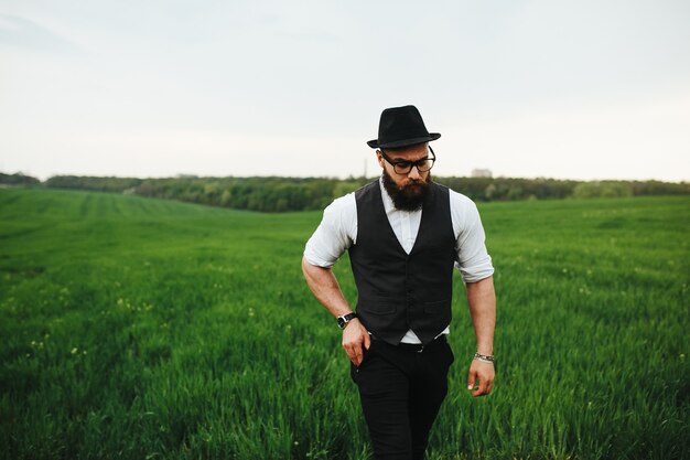 Un uomo con la barba e gli occhiali da sole che cammina sul campo