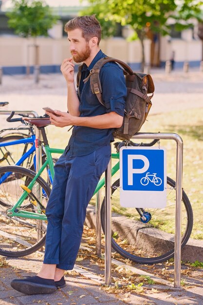 Un uomo con lo smartphone vicino al parcheggio delle biciclette.