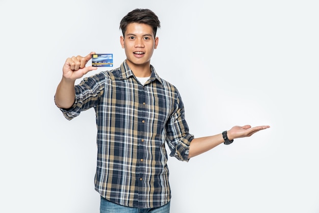 Un uomo con una camicia a righe apre la mano sinistra e tiene una carta di credito