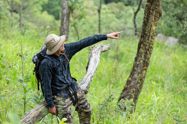 Un uomo di escursionismo felice cammina attraverso la foresta con uno zaino.