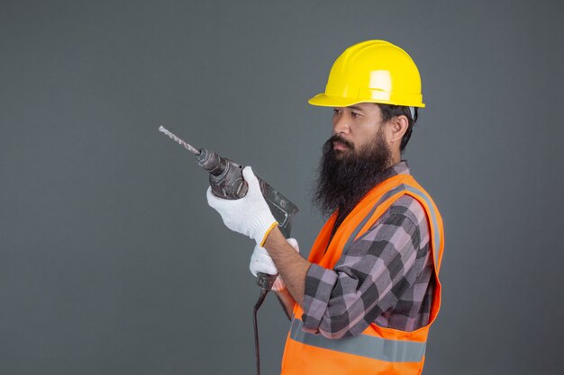 Un uomo di ingegneria che indossa un casco giallo con attrezzatura per l'edilizia su un grigio.