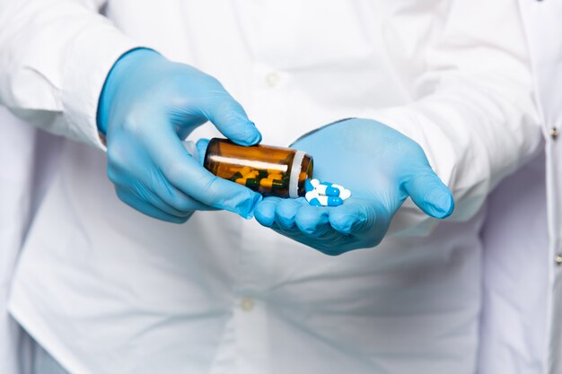 Un uomo di vista frontale che utilizza le pillole in camicia bianca nei guanti blu