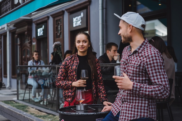 Un uomo e una ragazza stanno bevendo vino su una terrazza estiva in un caffè di strada. Coppia alla moda bere vino in caffè