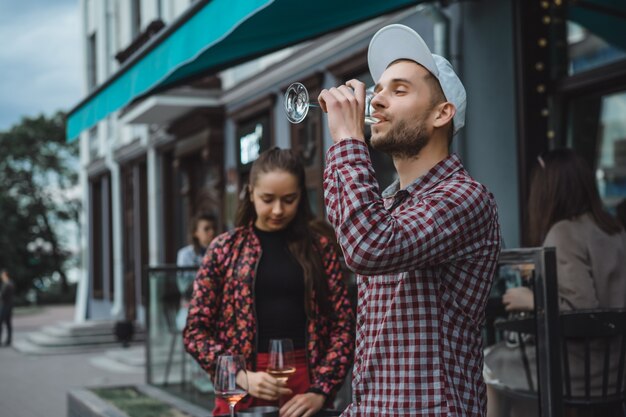 Un uomo e una ragazza stanno bevendo vino su una terrazza estiva in un caffè di strada. Coppia alla moda bere vino in caffè