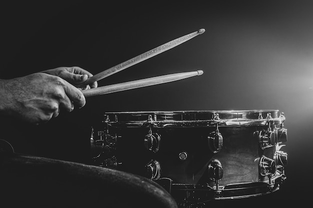 Un uomo gioca con i bastoncini su un tamburo, un batterista suona uno strumento a percussione, copia spazio, monocromatico.