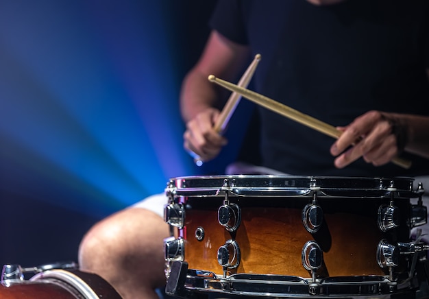 Un uomo gioca con i bastoncini su un tamburo, un batterista suona uno strumento a percussione, copia spazio.