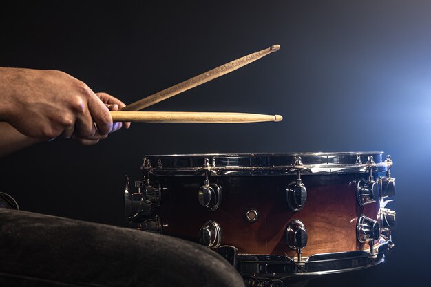 Un uomo gioca con i bastoncini su un tamburo, un batterista suona uno strumento a percussione, copia spazio.