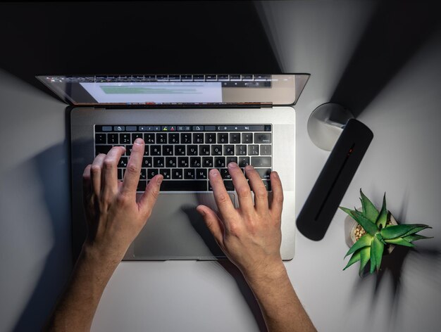 Un uomo lavora al computer di notte vista dall'alto