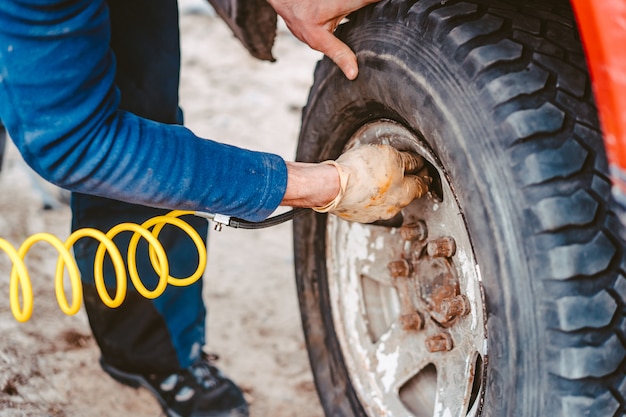 Un uomo pompa la ruota pneumatica con un compressore
