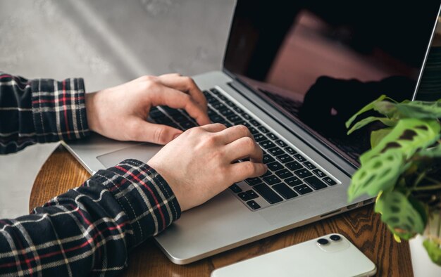 Un uomo preme i tasti di un computer portatile in primo piano