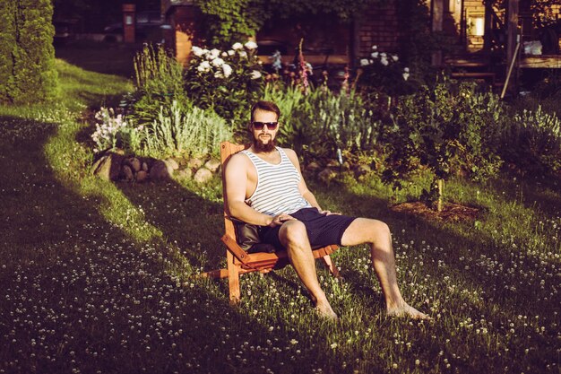 un uomo sta riposando in una casa di campagna. Un uomo con la barba gode del tramonto su un prato verde.