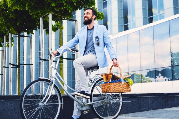 Un uomo su una bicicletta da città tiene un cestino da picnic.