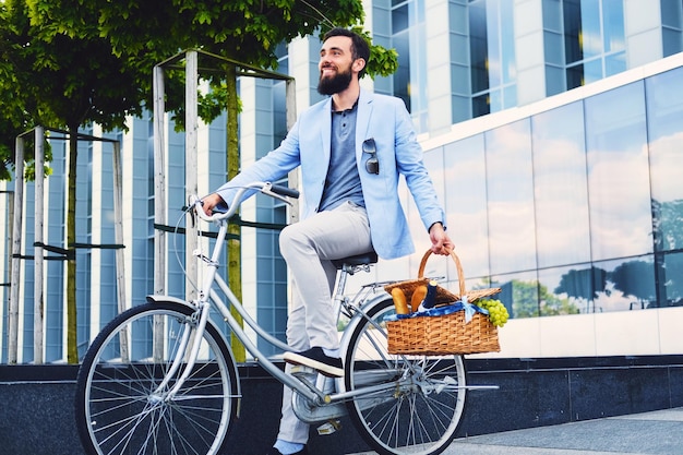 Un uomo su una bicicletta da città tiene un cestino da picnic.