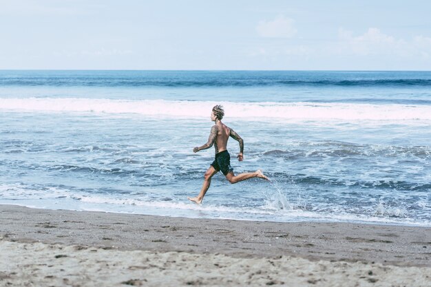 un uomo sulla costa dell&#39;oceano che corre lungo la riva del mare