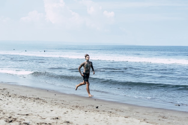 un uomo sulla costa dell&#39;oceano che corre lungo la riva del mare