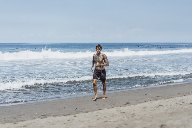 un uomo sulla costa dell&#39;oceano che corre lungo la riva del mare