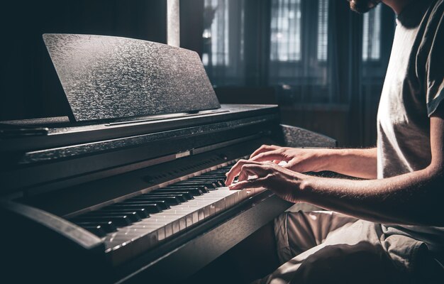 Un uomo suona un pianoforte elettronico in una stanza buia