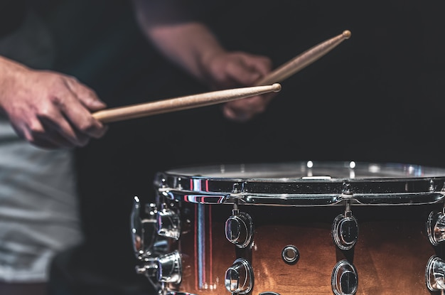 Un uomo suona un rullante con dei bastoncini, un batterista suona uno strumento a percussione, primo piano.