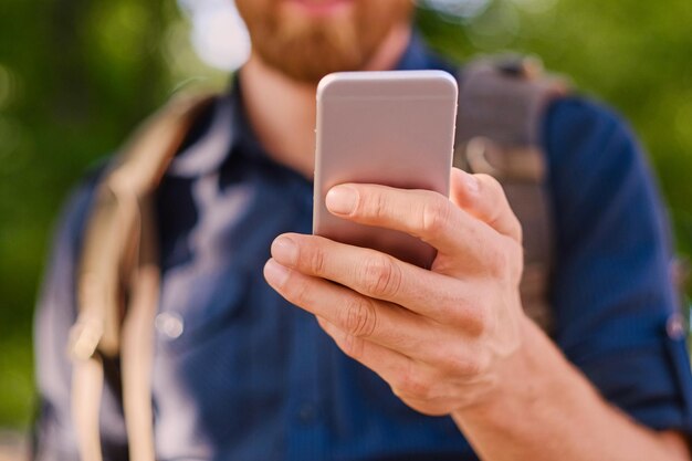 Un uomo tiene uno smartphone d'argento. Avvicinamento.